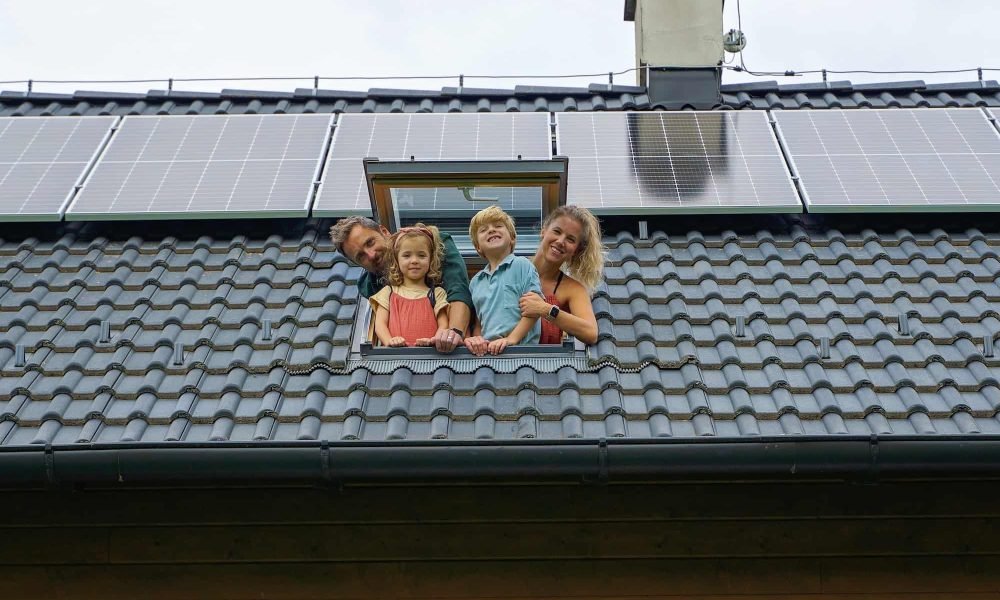 happy-family-leaning-out-from-skylight-window-in-their-new-house-with-solar-panels-on-the-roof.jpg
